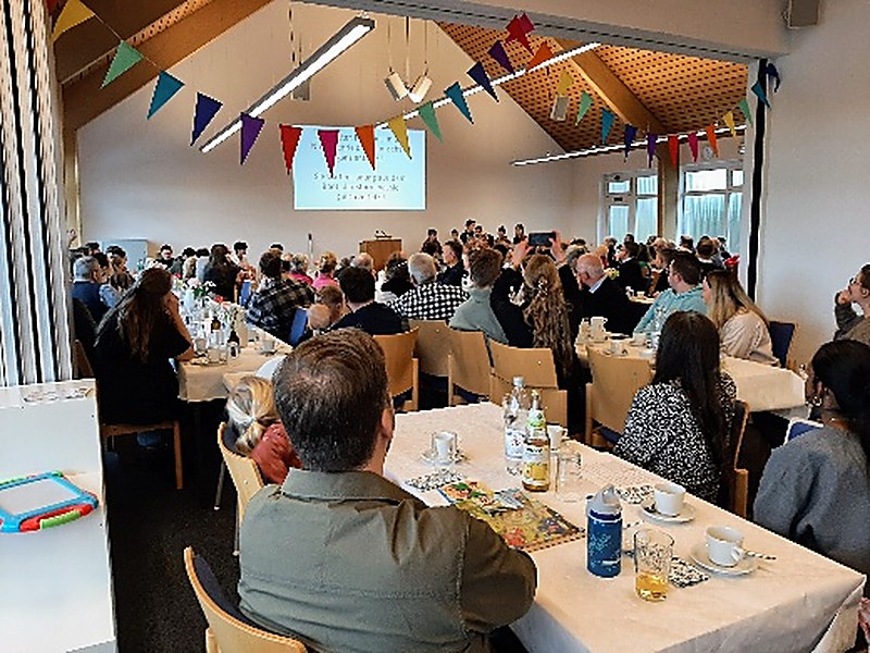 Der volle Saal bei der Sonntagschulfeier, festlich mit Wimpelketten geschmückt.